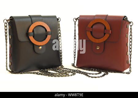 Black and Claret Red colored leather women shoulder bags with wooden buckles and metal chain straps together isolated on white - front view. Stock Photo