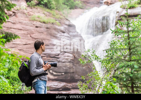 Hays creek falls waterfall in Redstone, Colorado during summer with man photographer standing with camera looking at view Stock Photo