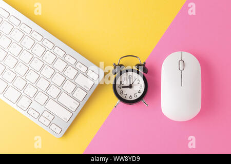 Computer keyboard and mouse with clock on yellow pink background, minimal, flat lay Stock Photo