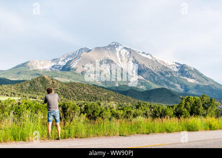 Man photographing mount Sopris mountain in Carbondale, Colorado town view with snow mountain peak and sky in summer during sunset Stock Photo