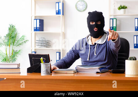 The male thief in balaclava in the office Stock Photo