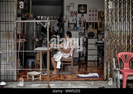 Woman working from home  as a seamstress modifying and reparing clothing. Thailand Southeast Asia Stock Photo