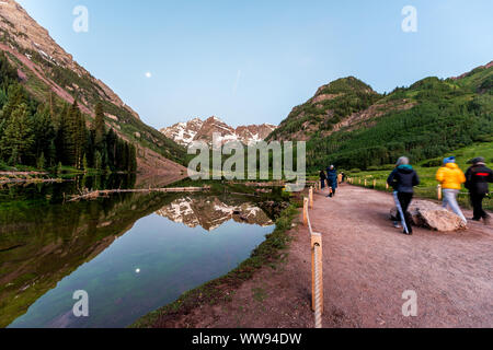 Aspen, USA - July 19, 2019: Maroon Bells lake wide angle view in Aspen, Colorado at blue hour with peak and snow in July 2019 summer and moon reflecti