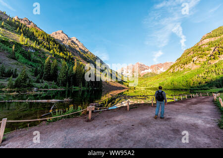 Maroon Bells lake in Aspen, Colorado with tourist man hiker walking in July 2019 summer on trail path road wide angle view Stock Photo