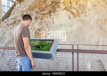 Jensen, USA - July 23, 2019: Information sign in Quarry visitor center exhibit hall and tourist man looking in Dinosaur National Monument Park of wall Stock Photo