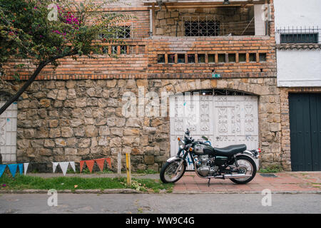 a motorcycle sits parked on the sidewalk in front of a garage door on a house in one of Bogotá's more affluent northern suburbs, Colombia Stock Photo