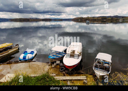 Boats sit on the mirror-like reflective waters of Laguna de Tota, Boyaca, Colombia Stock Photo