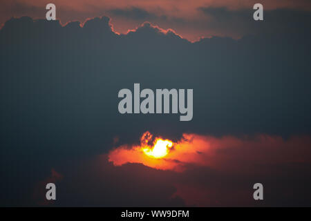 Majestic view of the sunset sky hiding the setting sun behind the clouds Stock Photo