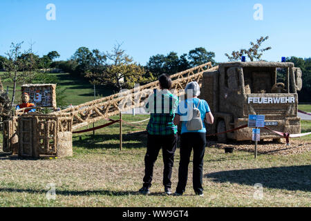13 September 2019, Baden-Wuerttemberg, Höchenschwand: Tourists stand in front of a straw fire ladder at the 10th Höchenschwander straw sculpture competition. Photo: Patrick Seeger/dpa Stock Photo