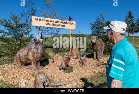 13 September 2019, Baden-Wuerttemberg, Höchenschwand: A tourist from Aarau in Switzerland stands in front of straw wolves at the 10th Höchenschwander straw sculpture competition. Photo: Patrick Seeger/dpa Stock Photo