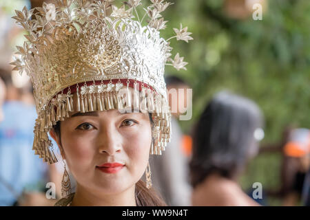 Zhangjiajie, China -  August 2019 : Cultural portrait of a beautiful chinese woman in a traditional chinese dress, wearing a golden decorated hat and Stock Photo