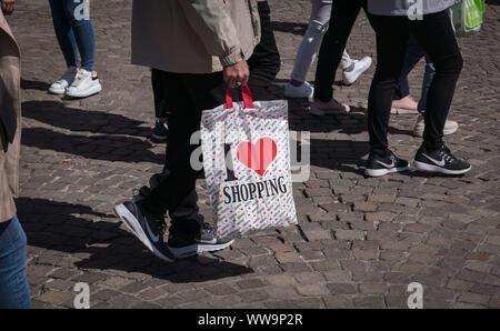 30 April 2019, Hessen, Frankfurt/Main: A man carries a plastic bag with the inscription 'I love shoppig' through the city centre. Photo: Frank Rumpenhorst/dpa Stock Photo