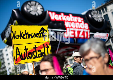 Frankfurt, Germany. 14th Sep, 2019. With a poster a woman demonstrates for the traffic turn, the word 'Autostadt' is crossed out with the poster, which looks like a place name sign. Behind it is written 'Verkehrswende Jetzt!' on a huge helium balloon in the shape of a car. On the first public day of the International Motor Show (IAA), thousands of demonstrators want to advocate a rapid turnaround towards climate-friendly mobility. Photo: Marius Becker/dpa Credit: dpa picture alliance/Alamy Live News Stock Photo