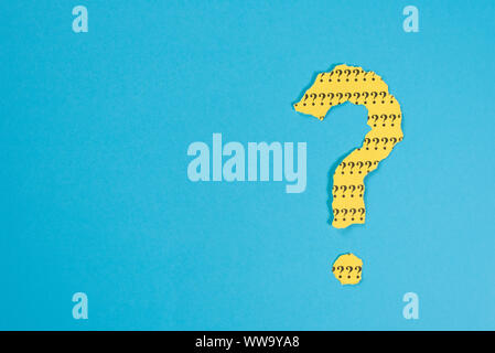 question mark symbol from a teared yellow paper on a blue background with copy space. Concept of FAQ, Q and A, Questions and riddle Stock Photo