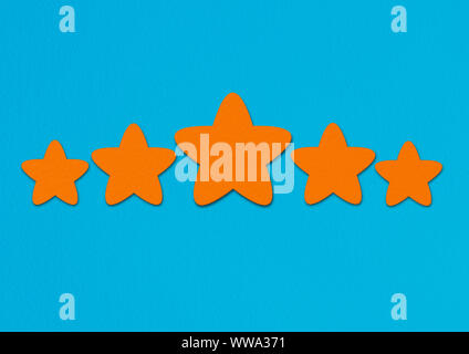 Orange stars rating on a blue background. A conceptual image of a level or achievement. Stock Photo