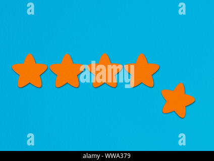 Orange stars rating on a blue background. A conceptual image of a level or achievement. Stock Photo