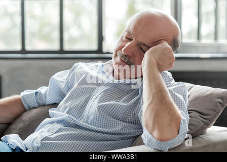 Tired senior hispanic man sleeping on couch, taking afternoon nap at the living room Stock Photo