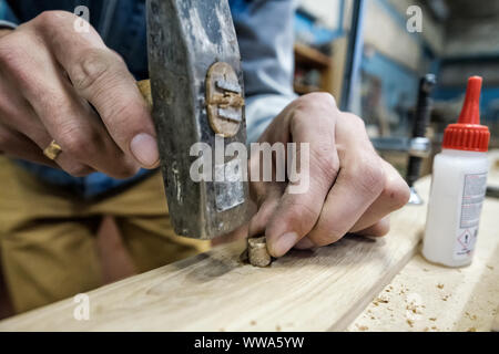 Carpenter using hammer, glue and wooden dowel. Close up view Stock Photo