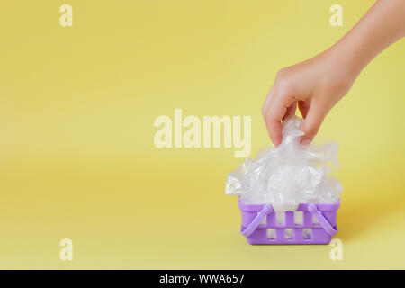 polythene bags in hand in shopping basket on yellow background. Stock Photo