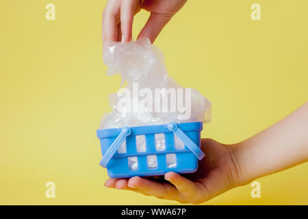 polythene bags in hand in shopping basket on yellow background. Stock Photo