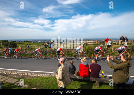 The city of Manchester is seen in the distance as competitors cycle across the top of Werneth Low Country Park during stage eight of the OVO Energy Tour of Britain from Altrincham to Manchester. Stock Photo