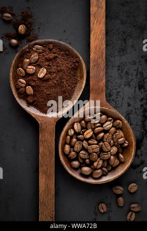 Ground coffee and coffee beans in two separate wooden spoons. Flat lay, overhead view Stock Photo