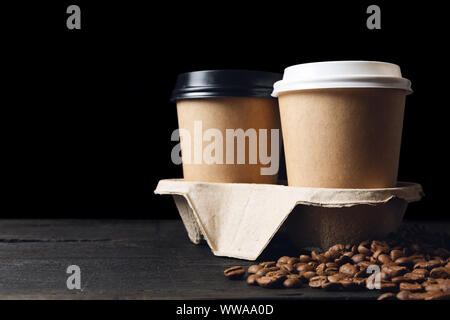 Two paper cups of coffee in cup holder and coffee beans on dark wooden table. Good quality coffee Stock Photo