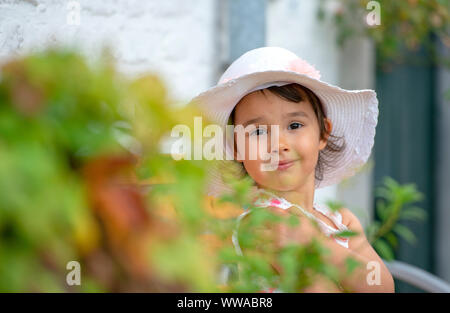 Adorable little girl wearing white hat on warm and sunny summer day Stock Photo