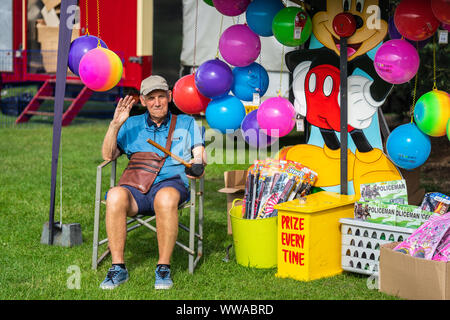 Bedford, Bedfordshire, UK June 2 2019. A fairground worker or theme park attendant works in a fairground or theme park, usually supervising a Stock Photo