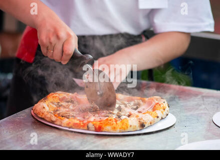 Girl cut pizza on table close up Stock Photo