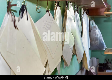 Professional tailor paper template set hanging on the wall in the workshop. Manufacturing leather goods, craft products. Stock Photo
