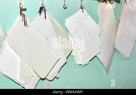 Professional tailor paper template set hanging on the wall in the workshop. Manufacturing leather goods, craft products. Stock Photo