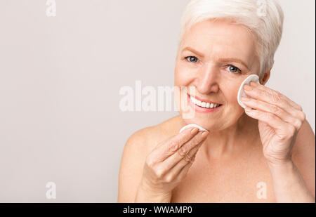 Elderly lady using cotton pad for removing make up Stock Photo