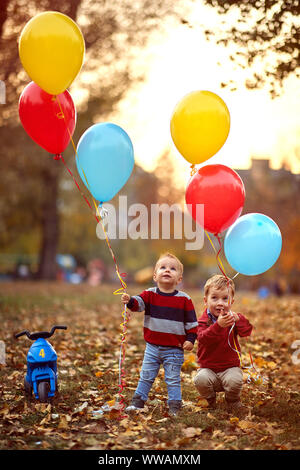 little child boy with a bunch of balloons in their hands in yellow autumn park Stock Photo