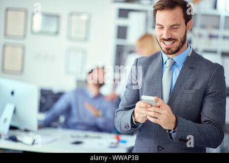 Smiling business man using mobile phone in office Stock Photo