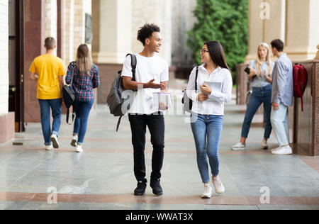 Diverse classmates chatting, walking after classes outdoors Stock Photo