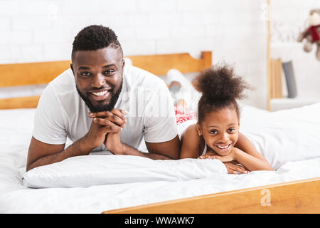 African father and daughter lying on bed on bed together Stock Photo