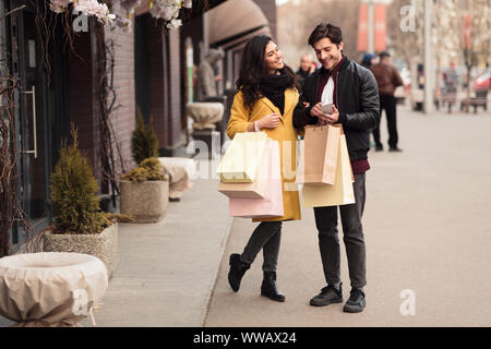 Consumerism concept. Young couple using smartphone outdoors Stock Photo