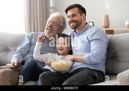 Happy three generation men family hold remote control watch tv Stock Photo