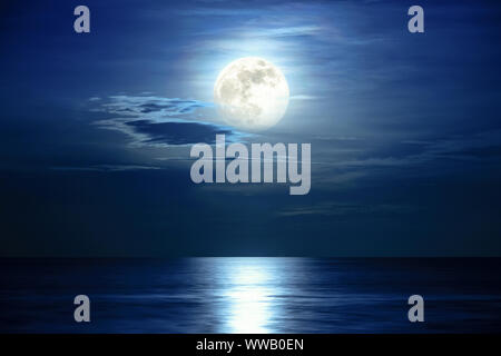 Super full moon and cloud in the blue sky above the ocean horizon at midnight, moonlight reflect the water surface and wave, Beautiful nature landscap Stock Photo