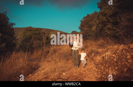 Young mother with little son walking on the trail in the mountains, camping in wild nature, active sportive family Stock Photo