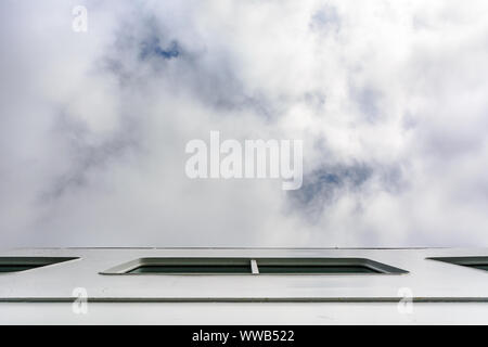 POV looking up to clouded blue sky from side of white ship from lower deck perspective. Stock Photo