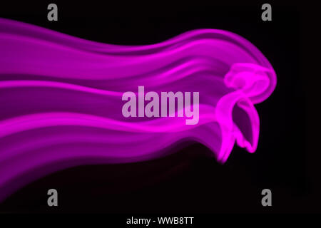 Neon pink flamingo LED lamp with wave in motion as blurred abstract background on black. Stock Photo