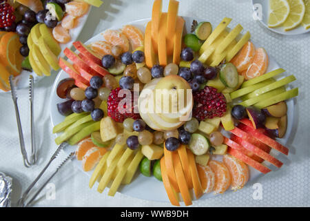 sliced fruits are inside the plate. Mandarin, grape, pomegranate, apple, orange Acca sellowiana Stock Photo