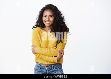 Comfort, romance and coziness concept. Cheerful lovely african-american girl in yellow sweater hugging herself, embracing body as feeling comfy Stock Photo