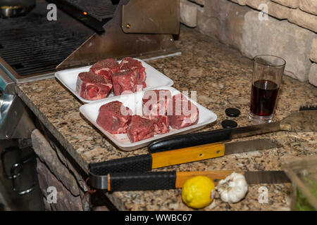 Steaks seasoned and prepared for grilling on an outdoor patio Stock Photo