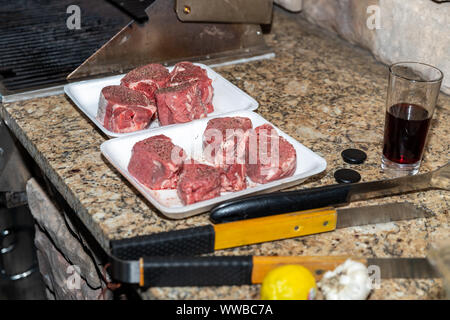 Steaks seasoned and prepared for grilling on an outdoor patio Stock Photo