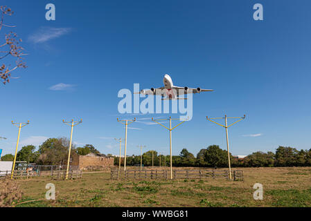 Emirates Airbus A380 super jumbo jet airliner plane landing at London Heathrow Airport in Hounslow, London, UK over dilapidated property and approach Stock Photo