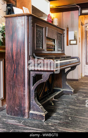 A very old upright acustic piano on a wooden floor, perspective view. Stock Photo
