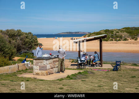 Two australian men cooking on a beach barbecue barbeque in Narrabeen on Sydney northern beaches, New South Wales,Australia Stock Photo